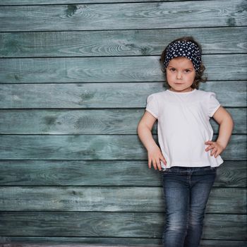 Stylish teenage girl leaning against a wall and looking at the camera