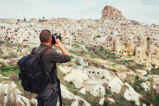 man photographs the ancient city and the castle Uchhysar dug from the mountains. Cappadocia, Turkey