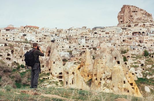 man photographs the ancient city and the castle Uchhysar dug from the mountains. Cappadocia, Turkey
