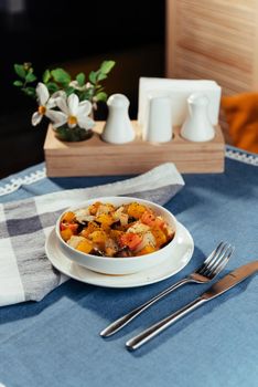 The cut fresh vegetables in a dish with spices and ingredients on the table.
