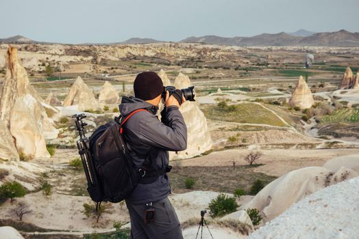 Photographer sandstone cliff and observing the natural landscape, Cappadocia, Turkey