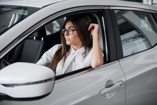 attractive young Caucasian woman looking at the camera from the front seat of the car