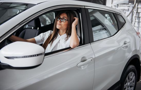 attractive young Caucasian woman looking at the camera from the front seat of the car