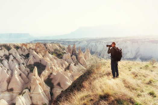 Photographer sandstone cliff and observing the natural landscape, Cappadocia, Turkey