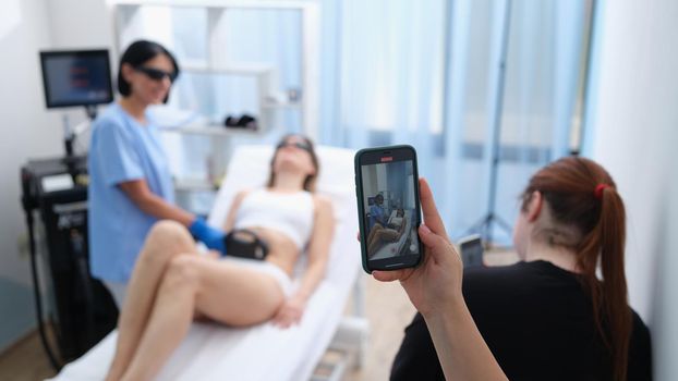 Smm manager filming laser hair removal video on mobile phone for social media ads closeup. Laser hair removal training concept