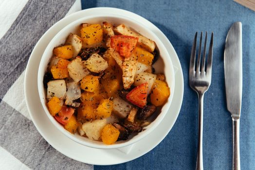 The cut fresh vegetables in a dish with spices and ingredients on the table.