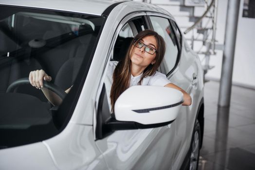 attractive young Caucasian woman looking at the camera from the front seat of the car
