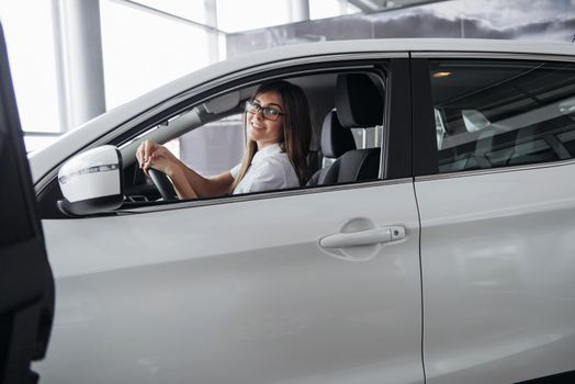 attractive young Caucasian woman looking at the camera from the front seat of the car