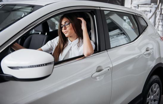 attractive young Caucasian woman looking at the camera from the front seat of the car