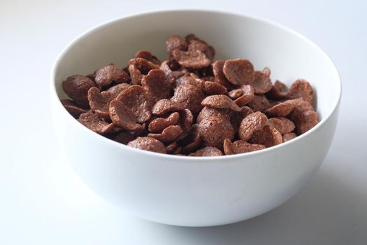 Chocolate breakfast cereal in a white bowl on table
