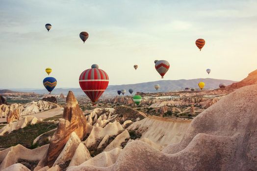 Hot air balloon flying over rock landscape at Cappadocia Turkey. Cappadocia with its valley, ravine, hills, located between the volcanic mountains in Goreme National Park.