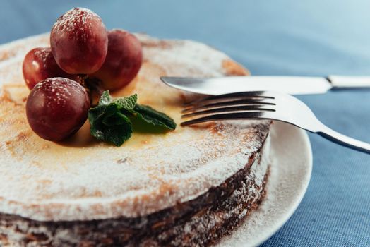 Fresh Creamy traditional cheesecake with grapes and sprinkled with powdered sugar.