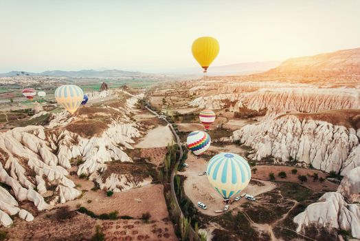 Colorful hot air balloons flying over Red valley at Cappadocia, Anatolia, Turkey. Volcanic mountains in Goreme national park.
