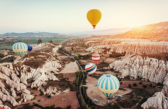 Colorful hot air balloons flying over Red valley at Cappadocia, Anatolia, Turkey. Volcanic mountains in Goreme national park.