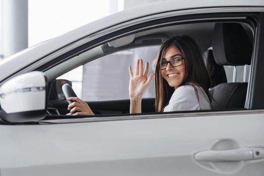 Pretty young woman driving her new car