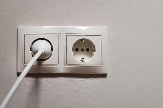 Two multifunctional white wall sockets are located in the center, one is free, the device is plugged into the second