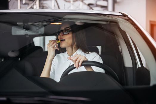 Pretty young woman driving her new car
