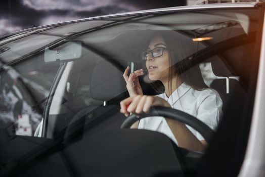 Pretty young woman driving her new car