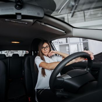 Pretty young woman driving her new car