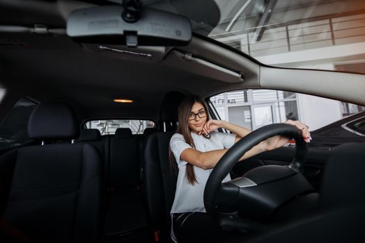 Pretty young woman driving her new car
