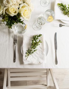 beautiful table setting for romantic dinner for two, with Linen napkins , white roses and boxwood. Close up
