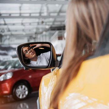 Young woman in her new car smiling.