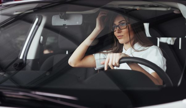 attractive young Caucasian woman looking at the camera from the front seat of the car
