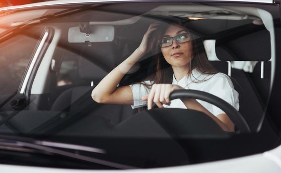 attractive young Caucasian woman looking at the camera from the front seat of the car