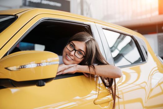 Young woman in her new car smiling.