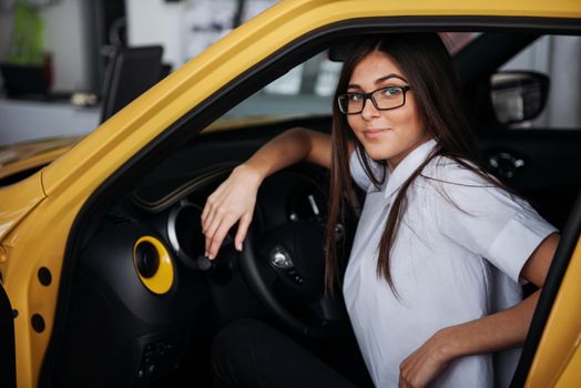 attractive young Caucasian woman looking at the camera from the front seat of the car