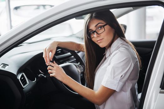 attractive young Caucasian woman looking at the camera from the front seat of the car