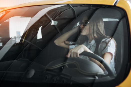 attractive young Caucasian woman looking at the camera from the front seat of the car