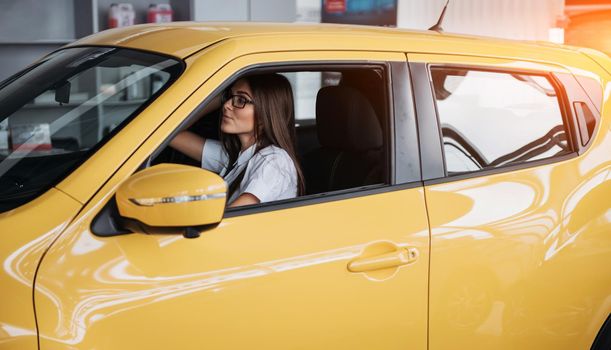 attractive young Caucasian woman looking at the camera from the front seat of the car