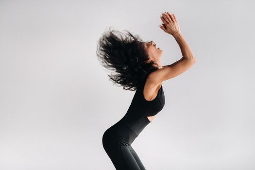 A woman in black sportswear is engaged in dynamic kali meditation in the Yoga hall.