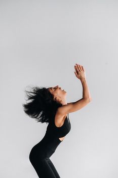 A woman in black sportswear is engaged in dynamic kali meditation in the Yoga hall.