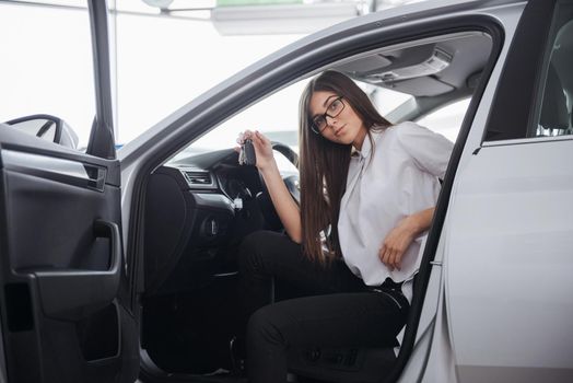 Young happy woman near the car with keys in hand - concept of buying car