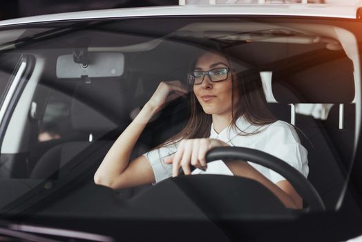 attractive young Caucasian woman looking at the camera from the front seat of the car