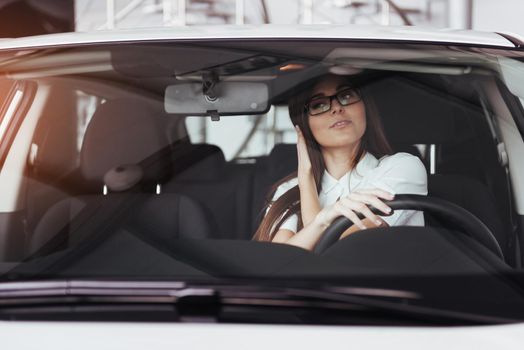 attractive young Caucasian woman looking at the camera from the front seat of the car