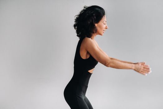 A woman in black sportswear is engaged in dynamic kali meditation in the Yoga hall.