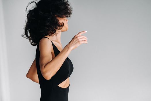 A woman in black sportswear is engaged in dynamic kali meditation in the Yoga hall.