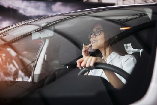 Pretty young woman driving her new car