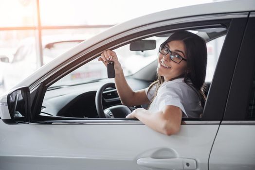 Young happy woman near the car with keys in hand - concept of buying car