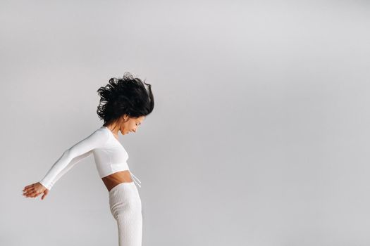 A woman in white sportswear is engaged in dynamic kali meditation in the yoga hall.
