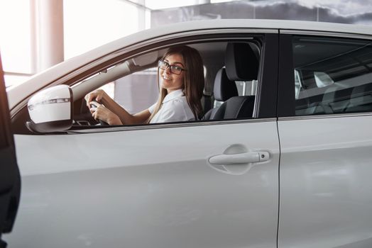 attractive young Caucasian woman looking at the camera from the front seat of the car