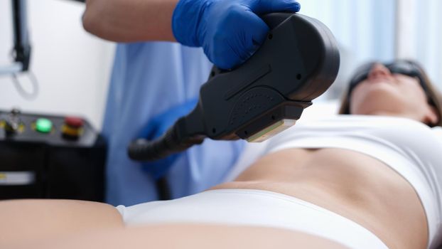 Cosmetologist removing unwanted hair from client body using laser closeup. Aesthetic medicine laser hair removal concept