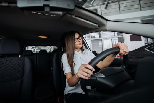 Pretty young woman driving her new car