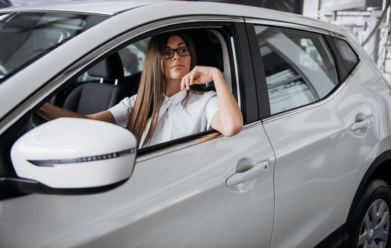 attractive young Caucasian woman looking at the camera from the front seat of the car