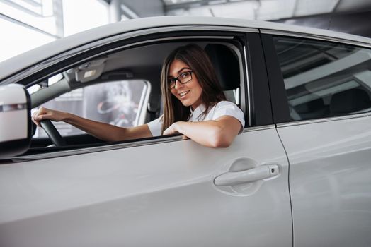 attractive young Caucasian woman looking at the camera from the front seat of the car