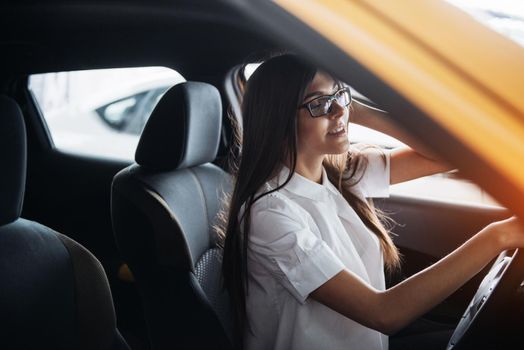 attractive young Caucasian woman looking at the camera from the front seat of the car