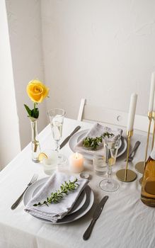 beautiful table setting for romantic dinner for two, with Linen napkins , yellow rose and boxwood. Close up
